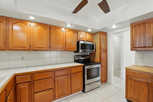 kitchen with light tile patterned floors, ceiling fan, appliances with stainless steel finishes, and tasteful backsplash