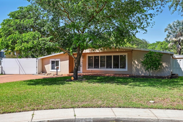 ranch-style house with driveway, stucco siding, a gate, and a front lawn
