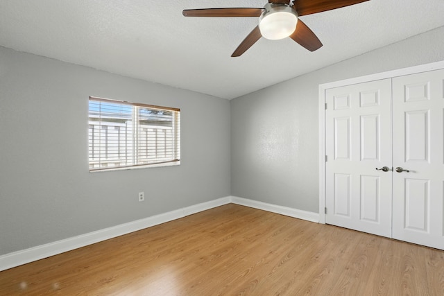 unfurnished bedroom with light wood-style flooring, baseboards, a closet, and a ceiling fan