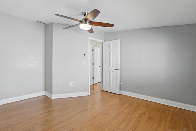 empty room featuring light wood-style floors, visible vents, baseboards, and ceiling fan