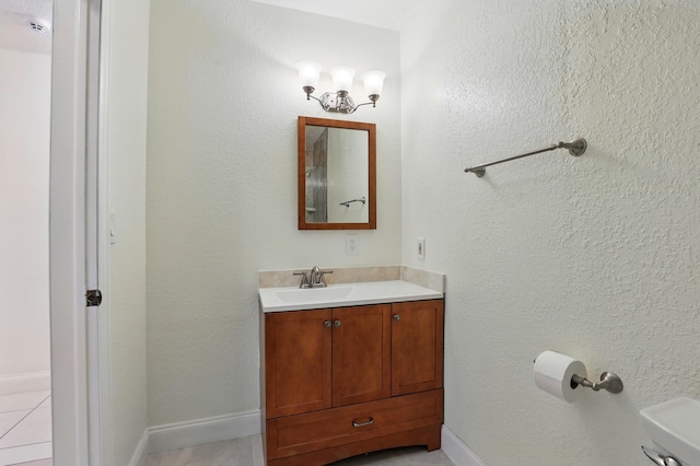 bathroom with toilet, vanity, baseboards, and tile patterned flooring