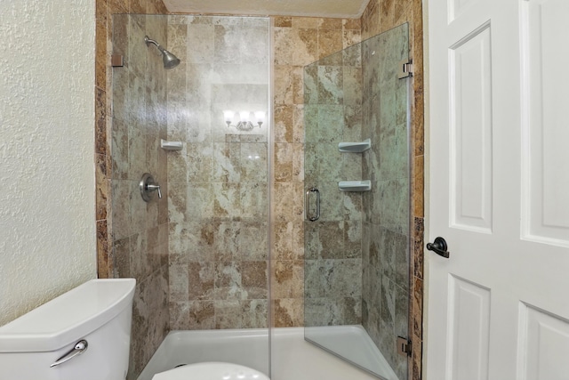 bathroom featuring toilet, a textured wall, and a stall shower