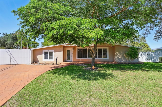 ranch-style house featuring a gate, a front lawn, fence, and stucco siding