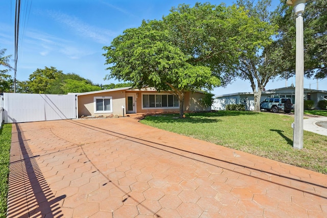 ranch-style house with a gate, driveway, fence, a front yard, and stucco siding