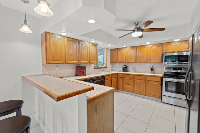 kitchen featuring tasteful backsplash, sink, kitchen peninsula, appliances with stainless steel finishes, and ceiling fan