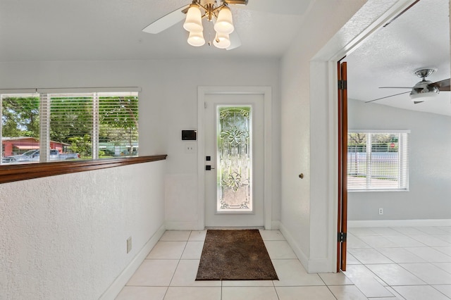 entryway featuring a ceiling fan, baseboards, light tile patterned floors, and a healthy amount of sunlight