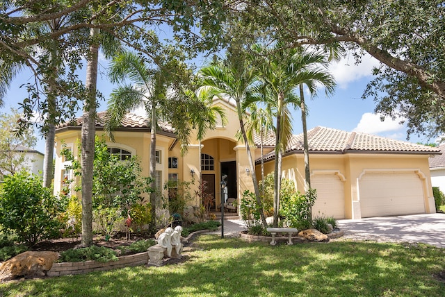 mediterranean / spanish house featuring a garage and a front yard