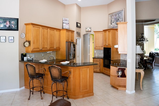 kitchen with black appliances, dark stone countertops, light tile patterned floors, and tasteful backsplash