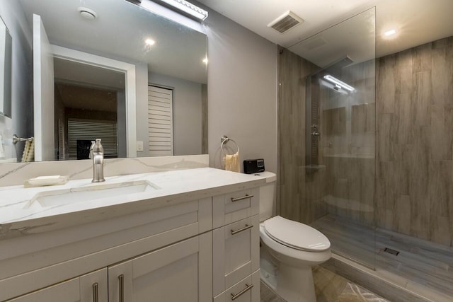 bathroom with a tile shower, vanity, and toilet