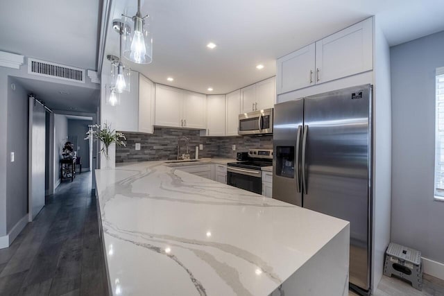 kitchen featuring appliances with stainless steel finishes, white cabinetry, hanging light fixtures, and sink