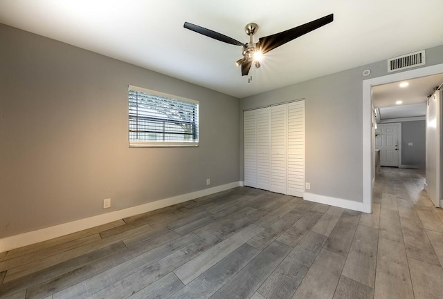 unfurnished bedroom featuring hardwood / wood-style floors, a closet, and ceiling fan