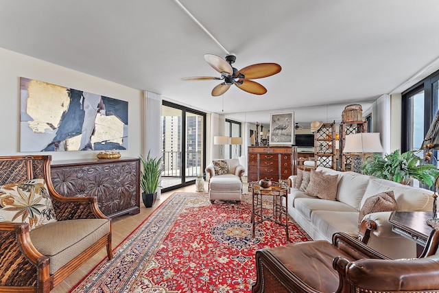 living area with expansive windows, ceiling fan, wood finished floors, and a wealth of natural light