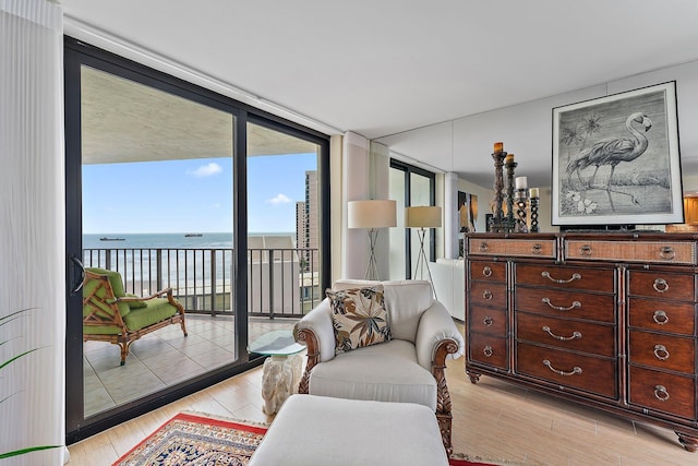 sitting room with light wood-style floors, floor to ceiling windows, and a water view