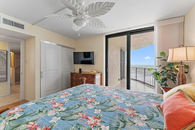 tiled bedroom with expansive windows, ceiling fan, visible vents, and access to exterior