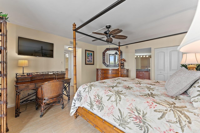 bedroom featuring a ceiling fan, ensuite bath, visible vents, and wood finished floors