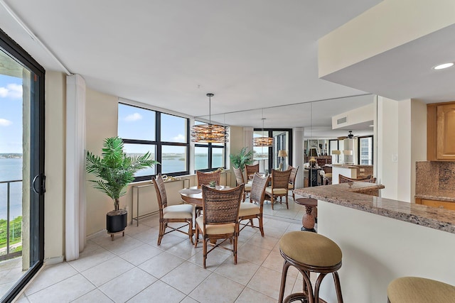 dining space with a water view, visible vents, and light tile patterned floors