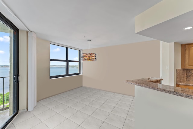 unfurnished dining area featuring a water view and light tile patterned floors