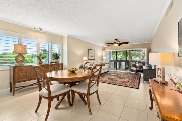 dining space featuring ceiling fan, a textured ceiling, ornamental molding, and light tile patterned flooring