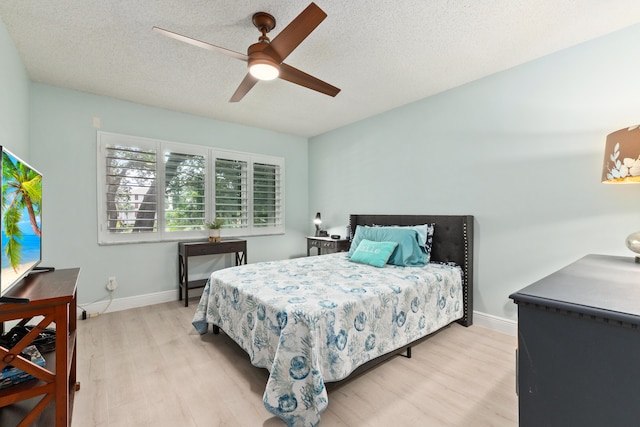 bedroom featuring light wood-type flooring, a textured ceiling, and ceiling fan