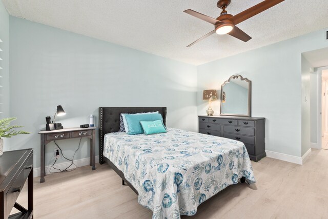 bedroom with a textured ceiling, ceiling fan, and light hardwood / wood-style flooring