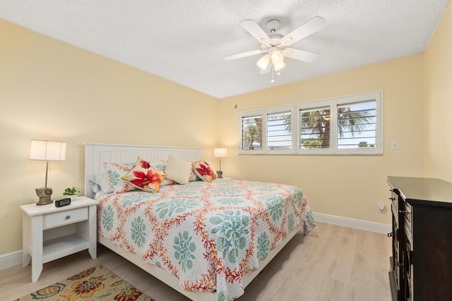 bedroom featuring light hardwood / wood-style flooring, ceiling fan, and a textured ceiling