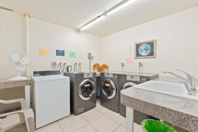 laundry area with light tile patterned floors, washer and clothes dryer, and sink