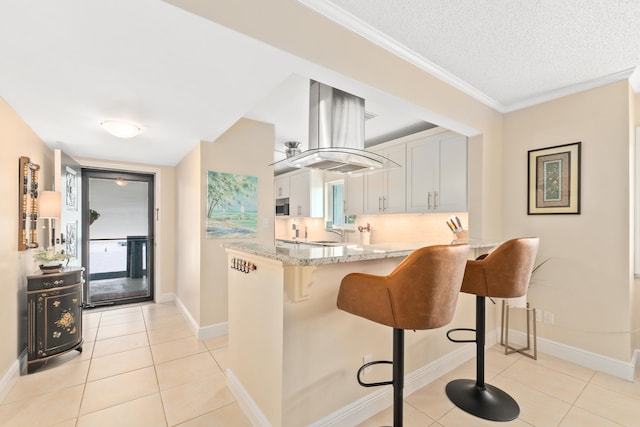 kitchen with white cabinetry, kitchen peninsula, light stone countertops, light tile patterned floors, and a textured ceiling