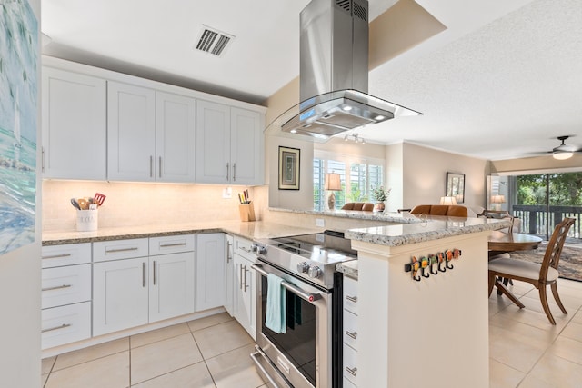 kitchen with ceiling fan, kitchen peninsula, island range hood, white cabinetry, and stainless steel electric stove