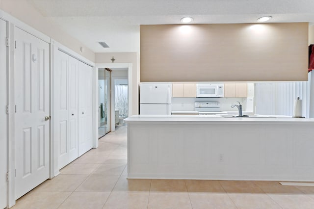 kitchen featuring kitchen peninsula, sink, light tile patterned flooring, and white appliances