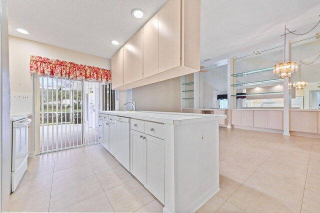 kitchen featuring an inviting chandelier, hanging light fixtures, range with electric stovetop, dishwasher, and white cabinets