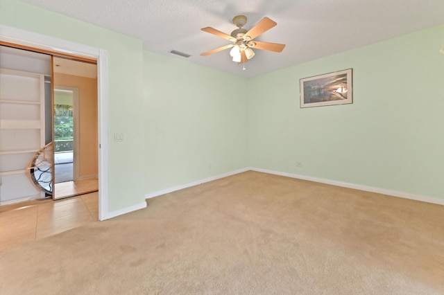 empty room with light carpet, a textured ceiling, and ceiling fan