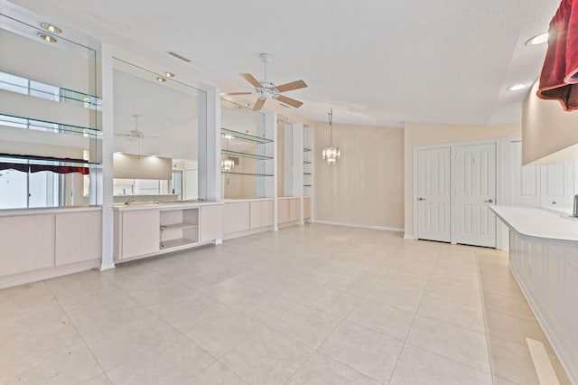 unfurnished living room with light tile patterned floors, ceiling fan with notable chandelier, and vaulted ceiling