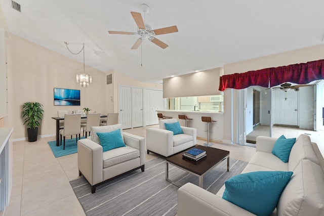 living room featuring lofted ceiling, ceiling fan with notable chandelier, and tile patterned floors