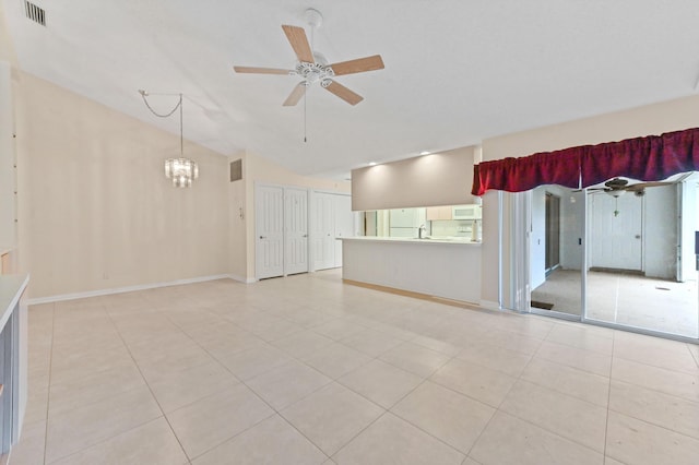 tiled empty room with lofted ceiling and ceiling fan with notable chandelier