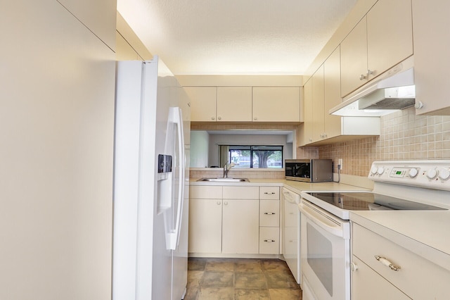 kitchen with tasteful backsplash, white appliances, a textured ceiling, cream cabinets, and sink