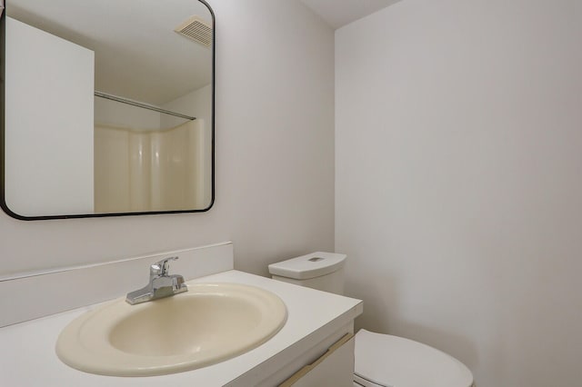 bathroom with walk in shower, vanity, and toilet