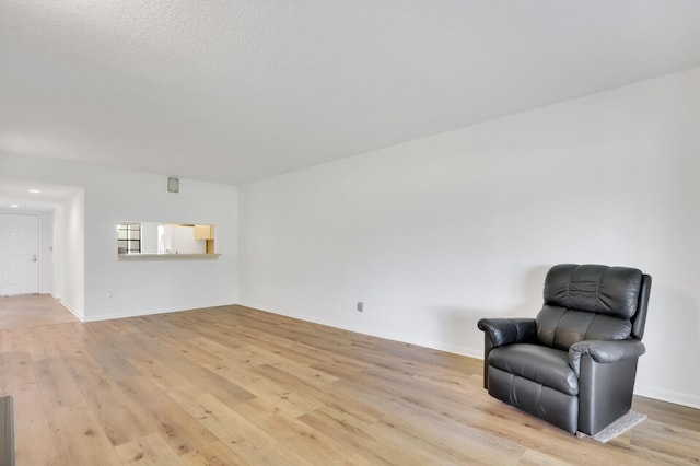 living area featuring light wood-type flooring and a textured ceiling