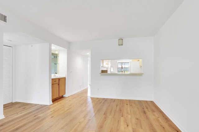 unfurnished living room with sink and light hardwood / wood-style floors