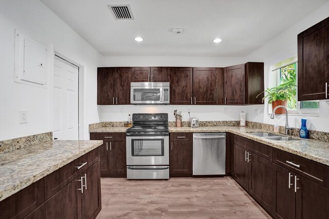 kitchen with appliances with stainless steel finishes, light hardwood / wood-style flooring, dark brown cabinets, and sink