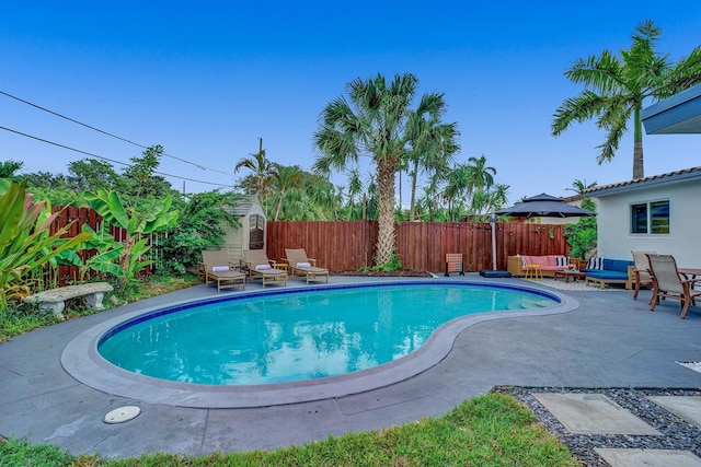 view of swimming pool with an outdoor living space, a storage unit, and a patio