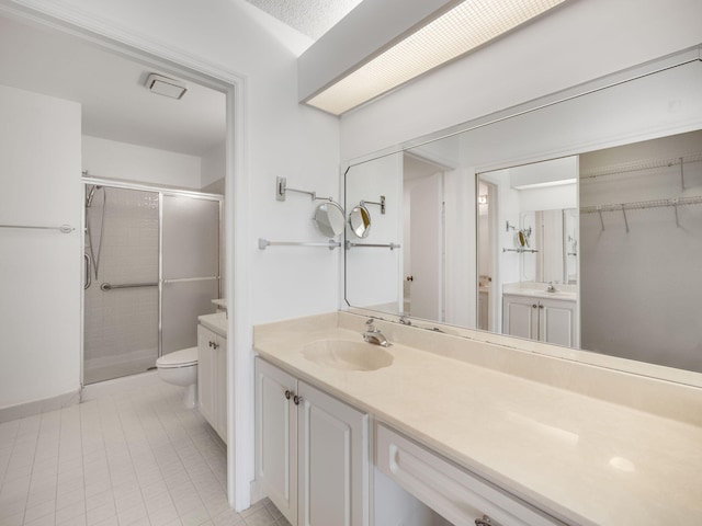 bathroom featuring tile patterned flooring, a shower with door, vanity, and toilet