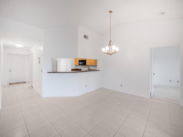 empty room with a notable chandelier, high vaulted ceiling, and light tile patterned flooring