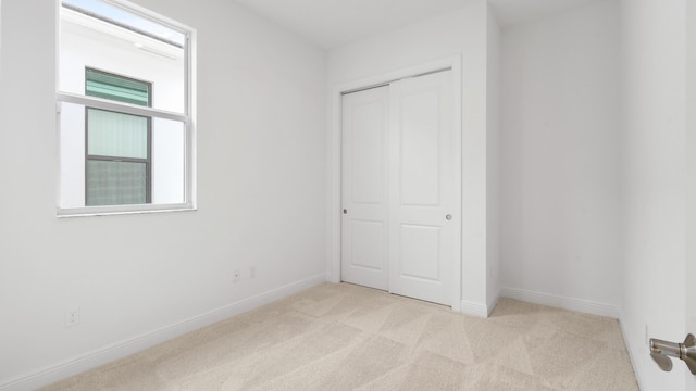 unfurnished bedroom featuring light colored carpet and a closet