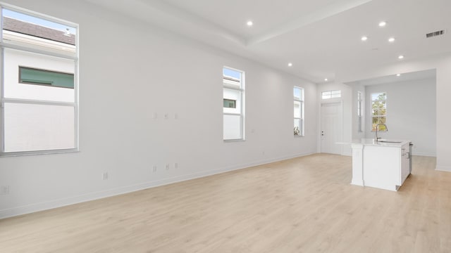 unfurnished living room featuring light wood-type flooring and sink