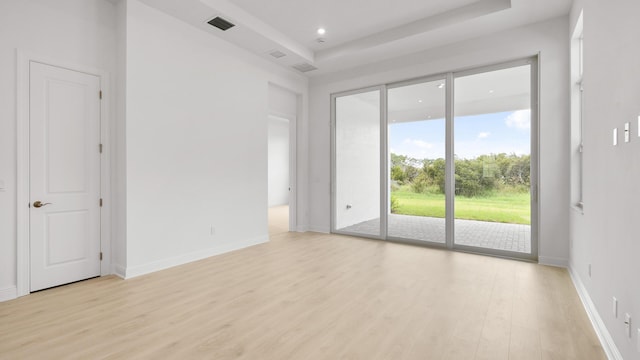 unfurnished room featuring a tray ceiling and light hardwood / wood-style floors