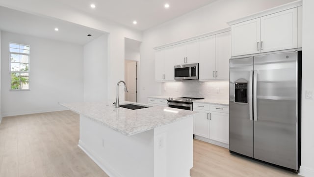 kitchen with white cabinets, stainless steel appliances, a kitchen island with sink, and sink