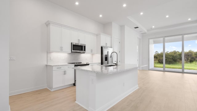 kitchen with sink, stainless steel appliances, light hardwood / wood-style flooring, a kitchen island with sink, and white cabinets