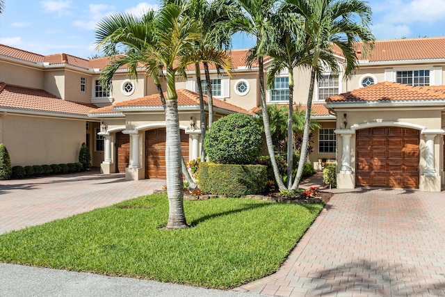 mediterranean / spanish-style home featuring a front yard and a garage