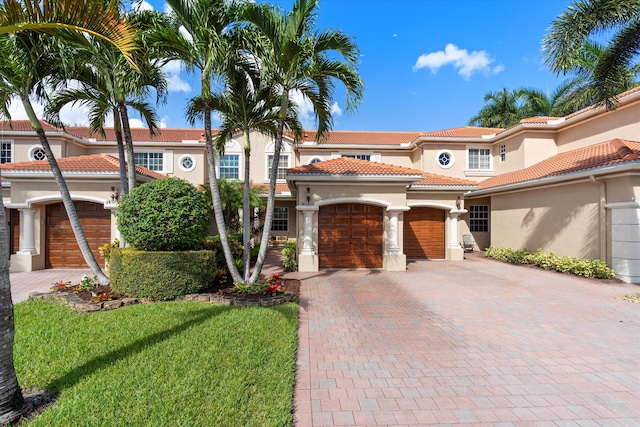 mediterranean / spanish house featuring a garage and a front lawn