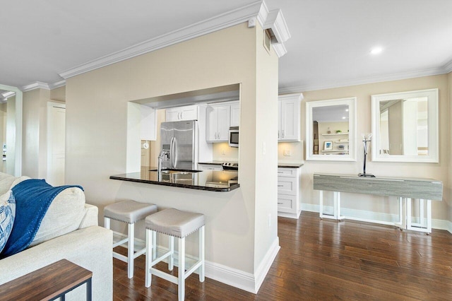 kitchen with white cabinetry, kitchen peninsula, appliances with stainless steel finishes, dark hardwood / wood-style flooring, and ornamental molding